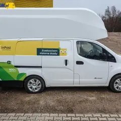 Biały Nissan e-NV200 InPost z hasłem "Zostawiam zielone ślady" i grafiką liścia.