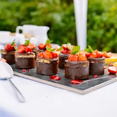 Catering przerwa kawowa: czekoladowe mini torty z truskawkami i cytrynowa tarta na eleganckim talerzu.