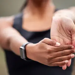 Une personne étire son poignet, peut-être pour soulager une douleur tendon poignet après un effort.