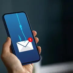 Telefon z ikoną koperty i haczykiem wędkarskim symbolizującym wyłudzenie pieniędzy. Uważaj na podejrzane wiadomości!