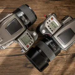 Two Hasselblad H2 camera bodies with lenses and accessories are laid out on a wooden surface.