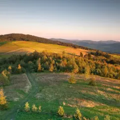 Zachód słońca nad Beskidem Niskim. Księżyc w pełni wisi na niebie, a złote światło oświetla pagórki i pola.