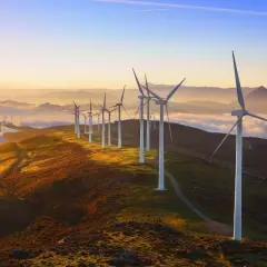 Wiatraki na wzgórzu o zachodzie słońca. Widać, jak działa turbina wiatrowa, łapiąc energię z wiatru.