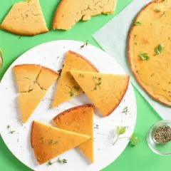 Une délicieuse socca coupée en parts, garnie d'herbes fraîches. Parfait pour une recette facile et savoureuse.