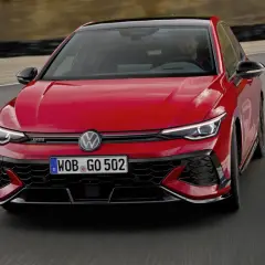 Czerwony Golf GTI Edition 50 na torze wyścigowym, z kierowcą za kierownicą, gotowy do ostrej jazdy.