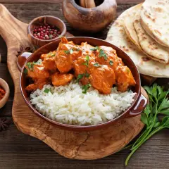 Aksamitny kurczak tikka masala z ryżem basmati, podany z plackami naan i aromatycznymi przyprawami.