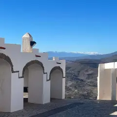 Arcos blancos y un paisaje montañoso nevado en la sierra de Almería bajo un cielo azul.