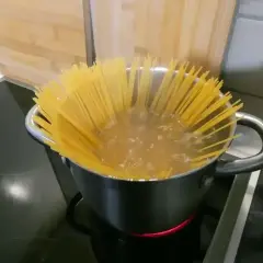 Długi makaron spaghetti gotuje się w garnku z wrzącą wodą. Czas gotowania jest kluczowy, by był idealnie al dente.