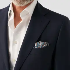En mörk kavaj med en vit skjorta och en färgglad näsduk i bröstfickan.