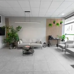 Nowoczesna poczekalnia kliniki medycznej z sofami, fotelami i roślinami.