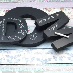 Czarna litera "D" z napisem "To jest literka do samodzielnego..." i rysunkami. Obok litery "N" z napisem "LOVE" i serduszkami, wykonane w stylu pismo kaligraficzne.
