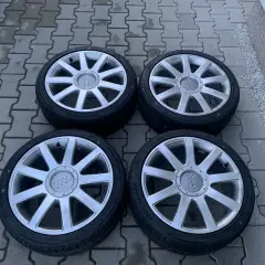 Cztery felgi aluminiowe z oponami do Audi A2. Rozmiar opon widoczny na jednej z nich to 205/55 R16.