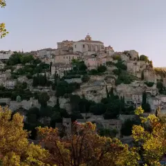 En vy över mysiga byar i Languedoc, Frankrike, med stenhus klättrande uppför en klippig kulle, omgivna av grönska.