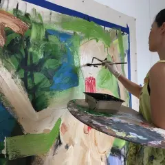 Lucy Liu artwork in progress: the artist adds bold strokes of black paint to a vibrant, abstract canvas, her palette ready for more color.