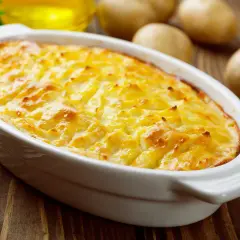 Herzhaftes Kartoffelgratin mit gekochten Kartoffeln, goldbraun überbacken in einer weißen Auflaufform.