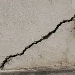 Une fissure importante traverse la façade d'un bâtiment, nécessitant une réparation urgente.