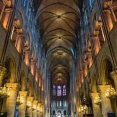 Intérieur de Notre Dame de Paris, avec ses voûtes gothiques, vitraux colorés et chandeliers. On se demande si peut on visiter Notre Dame de Paris.