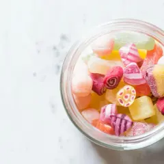 Słoik pełen kolorowych cukierków i żelek.