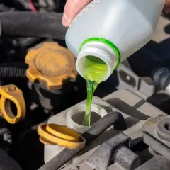 Se vierte líquido verde brillante en el depósito del coche. Esto demuestra para qué sirve el anticongelante del coche: mantener el motor a la temperatura adecuada.