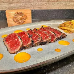 Tataki de ternera con costra de sésamo negro, acompañado de un toque de kimchi y salsa amarilla.