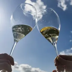 Deux flûtes de champagne pétillant levées en l'air, sous un ciel bleu éclatant. Un toast à Épernay !