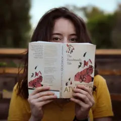 Dziewczyna w żółtej bluzce czyta książkę po angielsku "The Handmaid's Tale" Margaret Atwood.
