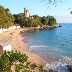 Plage de Noirmoutier avec cabines de bain, phare et mer bleue. Idéal pour savoir que faire à Noirmoutier.