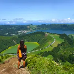 Mujer admira la vista de la **taska las negras**, un paisaje volcánico con lagos de colores y vegetación exuberante.
