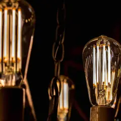 Bombillas led 15w de filamento, con luz cálida, colgadas de cadenas metálicas en la oscuridad.