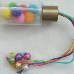 Buntes Rassel-Spielzeug zum selber machen 1 Jahr: Pompons in Fläschchen, bunte Schnüre mit Glitzerkugeln.