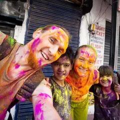 Fröhliche Familie feiert das Holi Festival in Indien, Gesichter und Kleidung bunt mit Pulverfarben bespritzt.