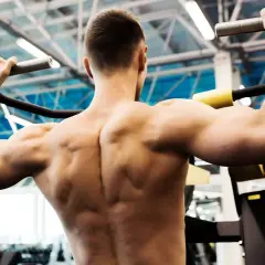 Un homme musclé effectue un tirage vertical, ses muscles dorsaux bien dessinés sous l'effort.