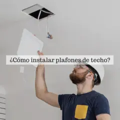 Hombre instalando bombillas plafon de techo, con casco y gafas de seguridad.