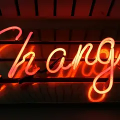 Néon rougeoyant "Change" pour illustrer comment changer de syndic en 5 étapes.