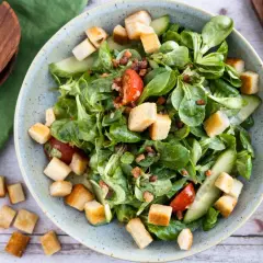 Frischer Feldsalat mit Speck und knusprigen Croutons, garniert mit Tomaten und Gurkenscheiben. Ein Genuss!