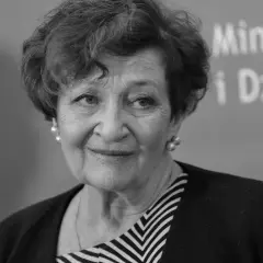 Uśmiechnięta Ewa Dałkowska, z perłami w uszach, na tle napisu "Ministerstwo i Dziedzictwo".