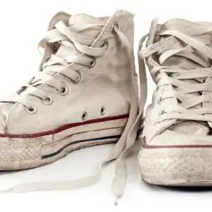 Zwei abgetragene, weiße Chucks mit Schnürsenkeln, bereit zum Chucks waschen.