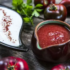 Två såser, en vit med paprika och en röd tomatbaserad, redo för ditt kebabsås recept. Tomater, vitlök och persilja i bakgrunden.