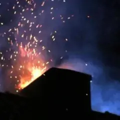 Jasny płomień wydobywa się z komina, a pojedyncze iskry z komina unoszą się w ciemne, zadymione niebo.
