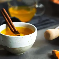 Eine Tasse goldener Ingwer-Kurkuma-Tee mit Zimtstange. Perfekt, um ihn abends zu trinken.