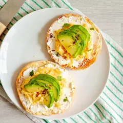 Deux toasts avec fromage frais, œufs brouillés et avocat. Un petit-déjeuner sain et savoureux, idéal pour maîtriser les calories.