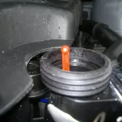 Zbiorniczek płynu chłodniczego w BMW E46. Pomarańczowa miarka wskazuje poziom płynu.