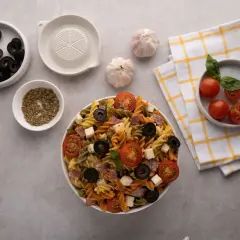 Deliciosa ensalada de pasta italiana con tomates, aceitunas, queso y salami. Ingredientes frescos listos para servir.