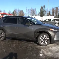 Szary Toyota bz4x test na tle stacji benzynowej i zaśnieżonego terenu.