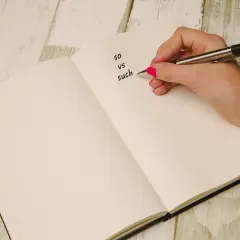 Dłoń pisze w zeszycie "so vs such". Nauka angielskiego bywa trudna, so...