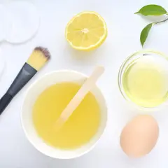 Ingredientes para una mascarilla de huevo para el pelo: huevo, limón, aceite y brocha.