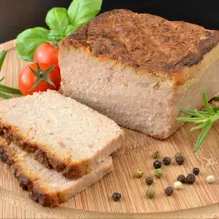 Pyszny pasztet w piekarniku, pokrojony na plastry, z pomidorkami, rozmarynem i pieprzem na desce.