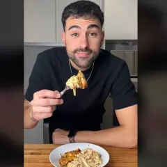 Hombre sonriendo mientras prueba unos deliciosos macarrones con pollo.