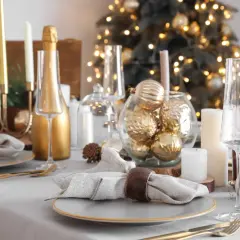Festlich gedeckter Tisch Weihnachten mit goldenen Kugeln, Kerzen und Champagner. Ein eleganter Blickfang für die Feiertage.