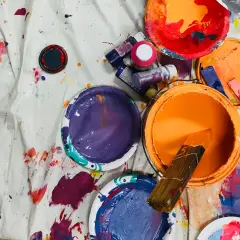 Pots de peinture acrylique ouverts, éclaboussés sur une toile. La durée conservation peinture acrylique dépend de son stockage.